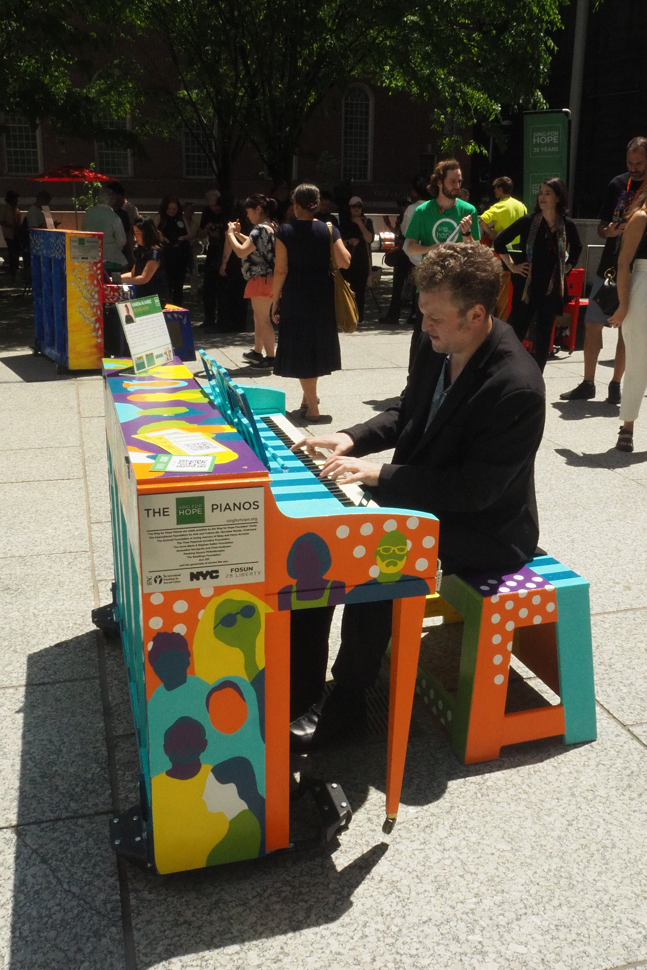 Tristan Cano performing on a hand-painted Sing for Hope piano in a public plaza during the organization's 25th anniversary celebration